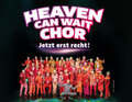 Eine große Gruppe von Menschen in bunten Outfits posiert vor einem dunklen Hintergrund. Oben steht: Heaven Can Wait Chor - Jetzt erst recht!
