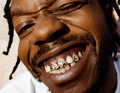 Person lächelt breit mit auffälligem Zahnschmuck und geschlossenen Augen, zeigt eine fröhliche und entspannte Ausstrahlung.