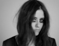 Schwarz-weiß-Bild einer Person mit langen Haaren, dramatischem Augen-Make-up und verträumtem Blick.