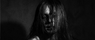 Schwarz-weiß Porträt einer Person mit nassem Haar, teils verdecktem Gesicht, dramatische Beleuchtung, emotionale Atmosphäre.