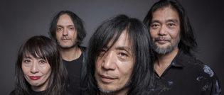 Vier Personen mit langen Haaren stehen nebeneinander und schauen in die Kamera vor einem grauen Hintergrund.