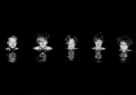 Fünf Personen schauen aus dunklem Wasser, nur ihre Gesichter sind sichtbar. Ihre Spiegelungen erscheinen auf der Wasseroberfläche.