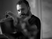 Ein Mann mit Bart hält einen Topf in der Hand und schaut konzentriert. Das Bild ist in Schwarz-Weiß gehalten.