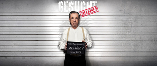 Ein Mann in weißem Hemd hält ein Schild mit der Aufschrift 'Zu leise? Tour 2022' vor einer polizeilichen Messwand.